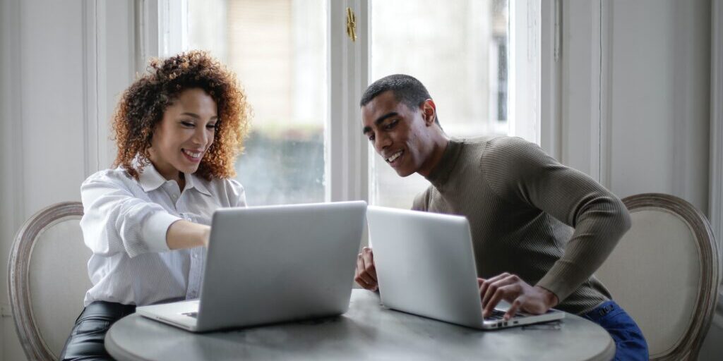 positive-young-ethnic-colleagues-using-laptops-on-round-3967033